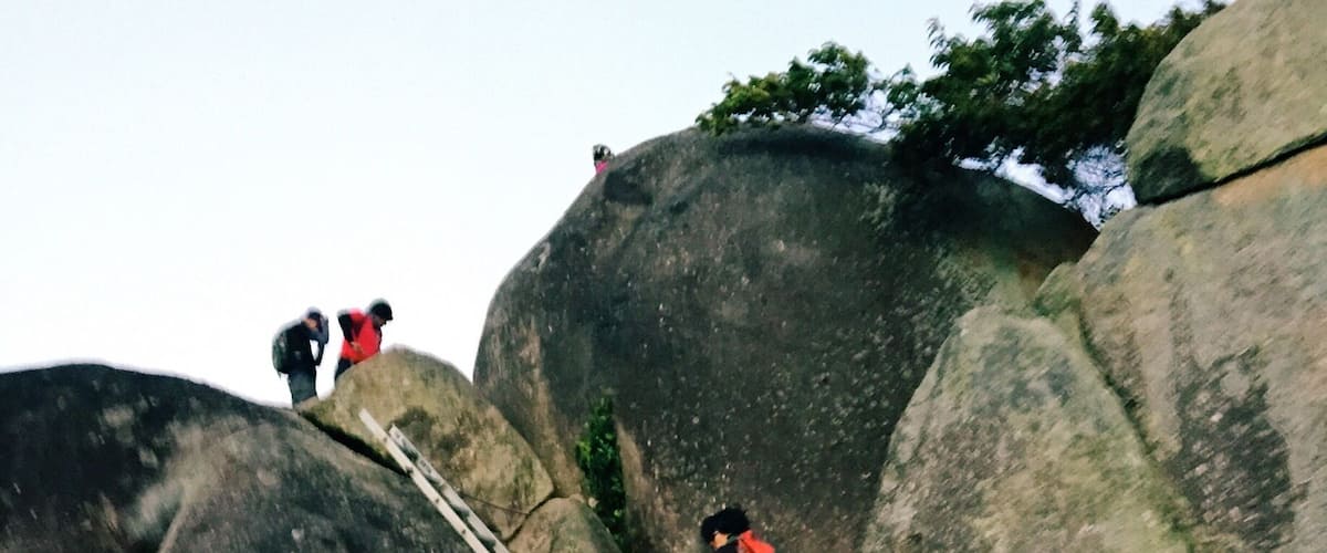 A person climbing a rocky mountain with a ladder.