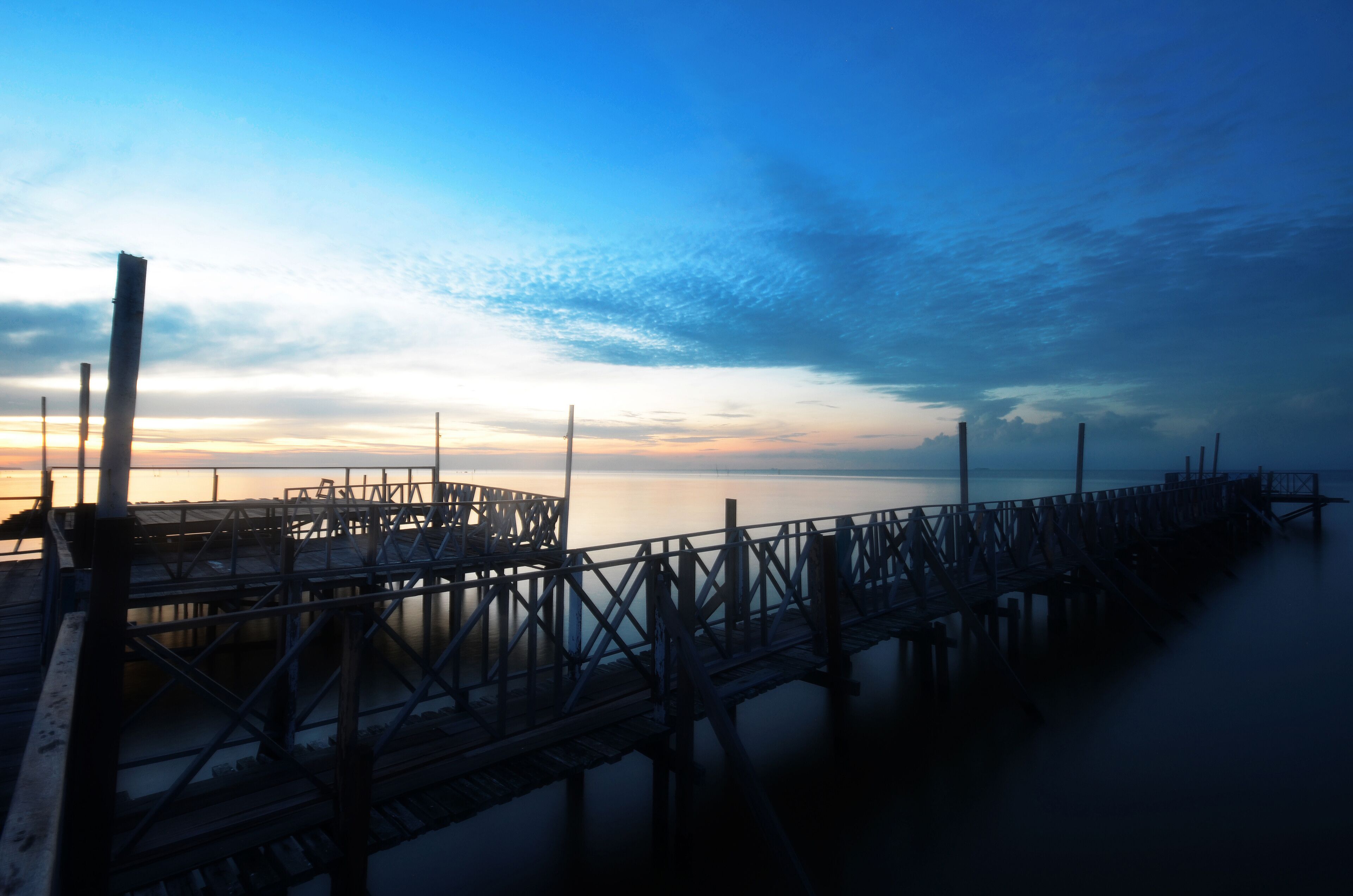 A pier extending into calm waters at sunset.