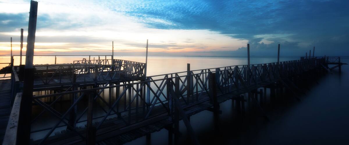 A pier extending into calm waters at sunset.