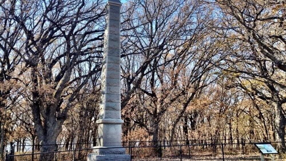Un grand monument de pierre, entouré d’arbres sans feuilles, dans un parc.