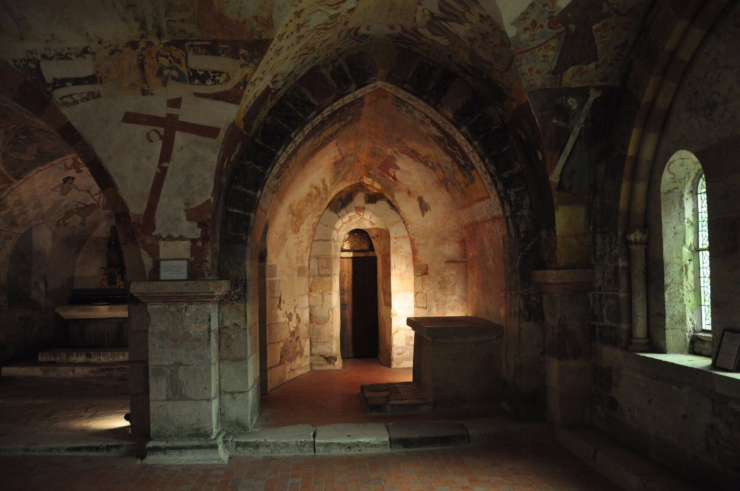 An ancient church interior with arched ceilings, stone walls, and a central doorway.