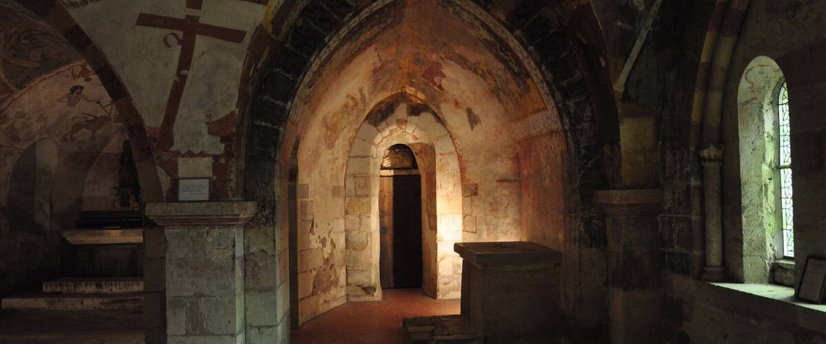 An ancient church interior with arched ceilings, stone walls, and a central doorway.