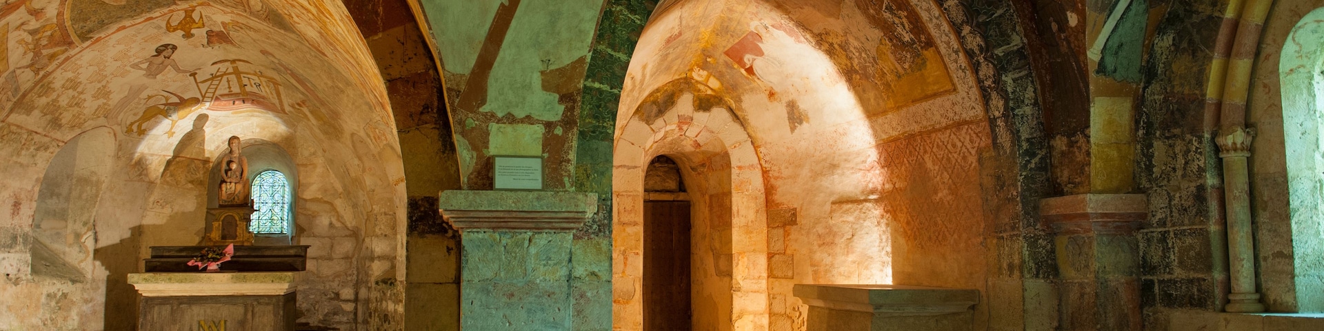 Ein Innenraum mit Gewölbedecken, Steinsäulen und einem zentralen Altar.