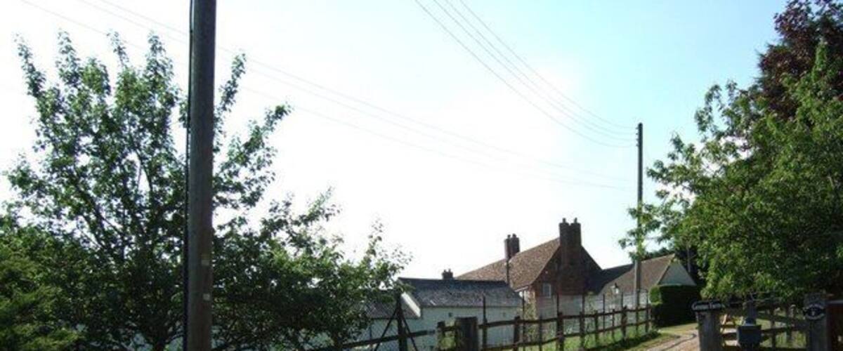A rural road with a wooden fence, houses, and a clear sky.