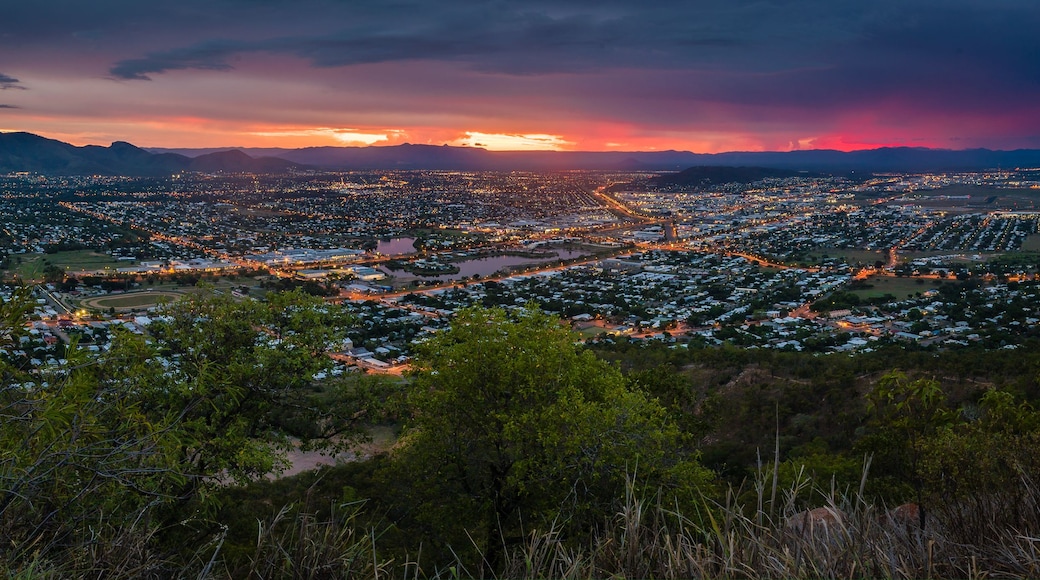 Une vue sur une ville au crépuscule, avec un coucher de soleil sur les montagnes.