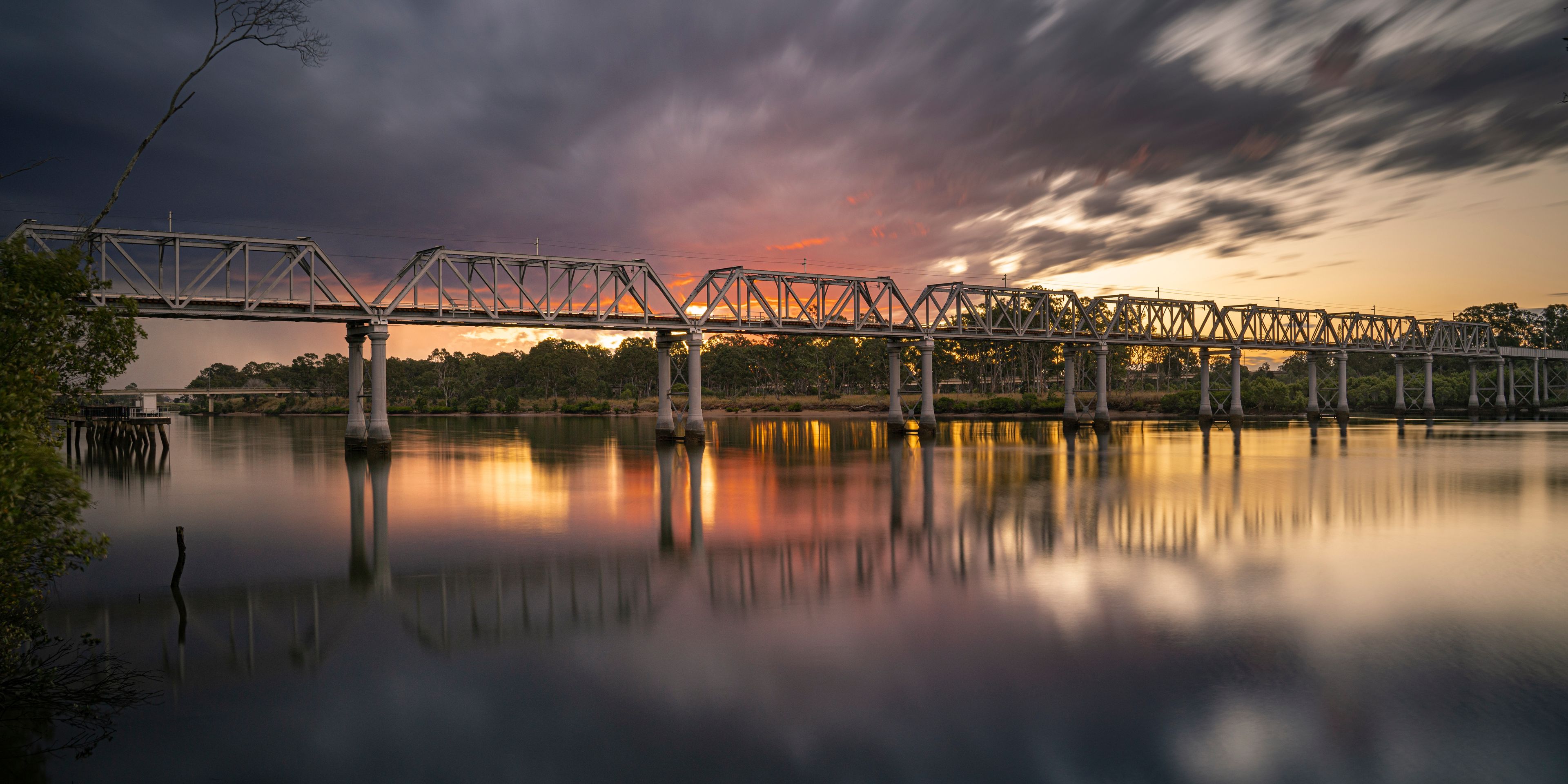 Sunset over a rail bridge crossing over the Burnett River, Bundaberg, Queensland