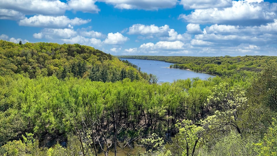 A river winding through a forested valley with a clear sky above.