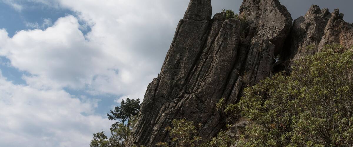 A person standing on a rocky outcrop with a cloudy sky in the background.