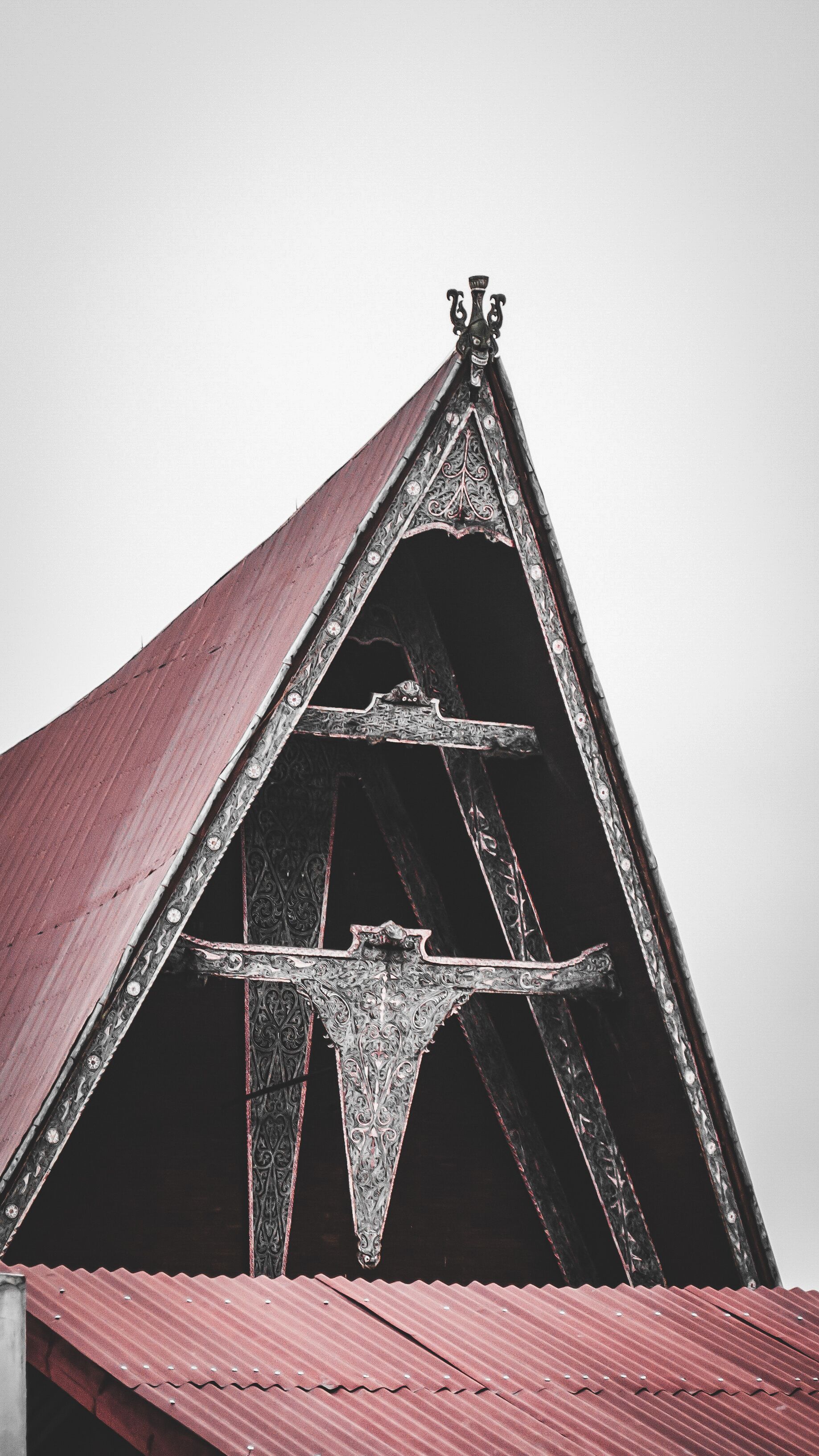 A triangular roof with ornate metalwork and a red corrugated metal roof.