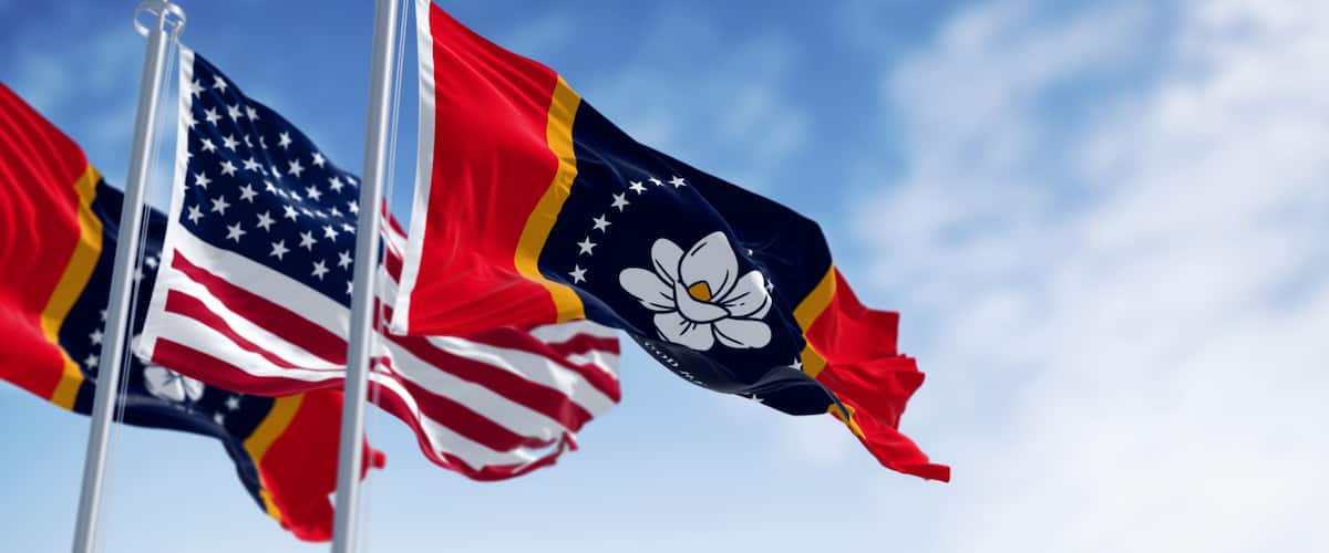 Two flags on flagpoles against a blue sky.