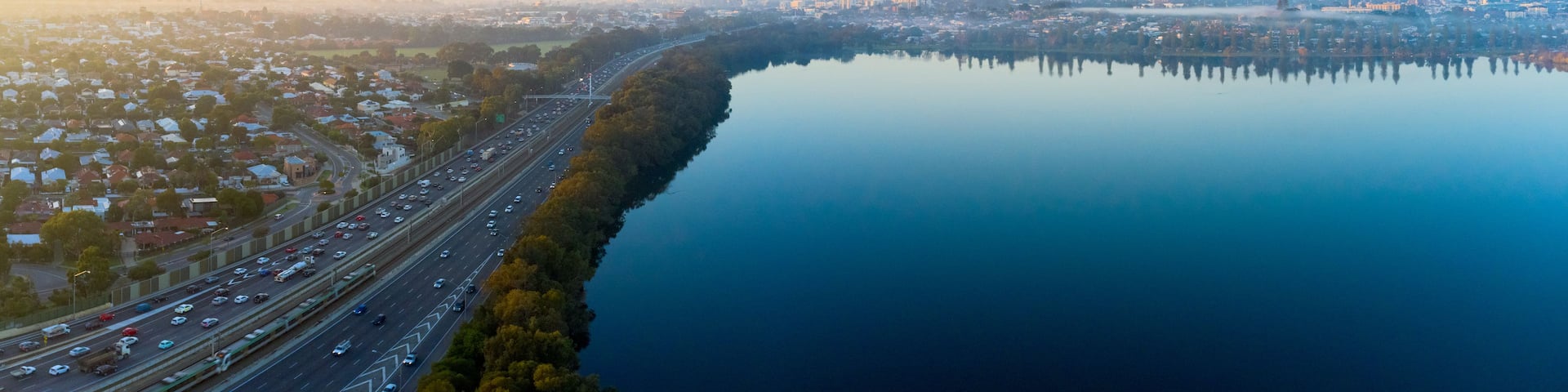 A river with a bridge, a highway, and a city skyline in the distance.