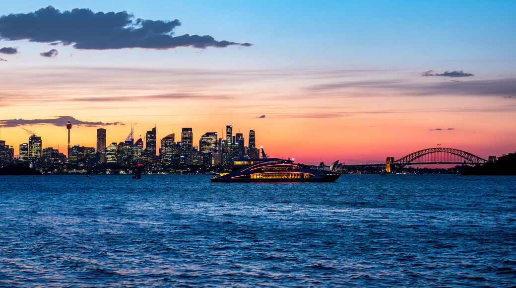 Un atardecer sobre el horizonte urbano con un puente destacado.