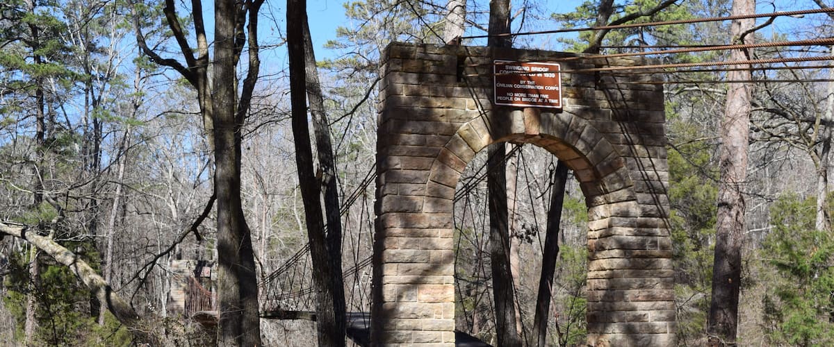 A stone archway with a historical marker in a wooded area.