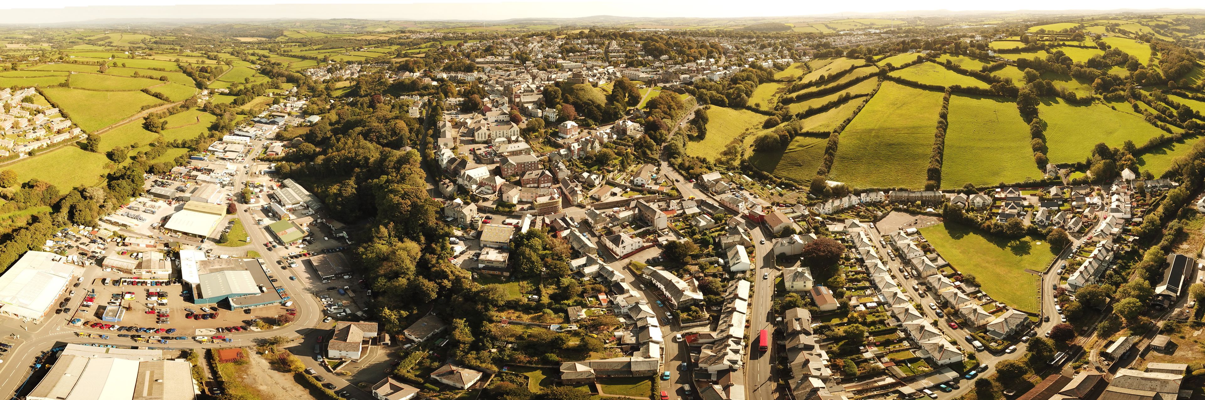 Aerial view of the historic town of Launceston with its traditional stone buildings surrounded by lush green fields and rolling hills in Launceston, England, United Kingdom.