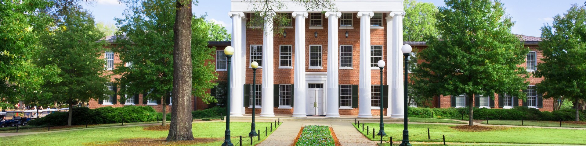 Lyceum Building at Ole Miss at the end of parallel sidewalks with early spring flowers