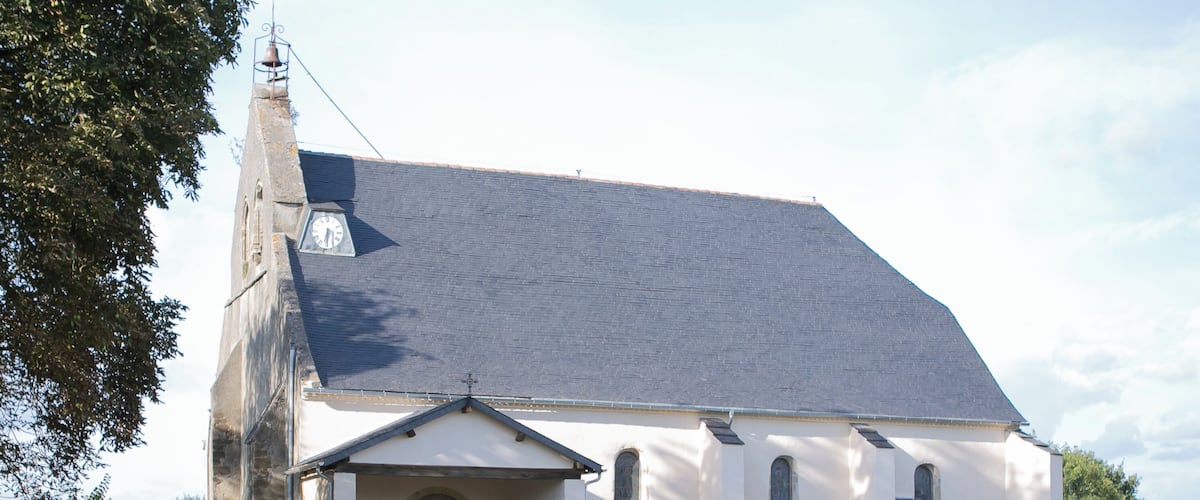 A white church with a bell tower and a car parked in front.