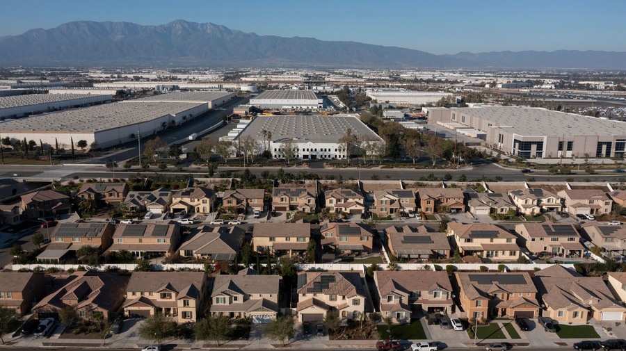Jurupa Valley, California, USA - November 9, 2024: Afternoon sun shines on newly constructed industrial warehouses and suburban homes.