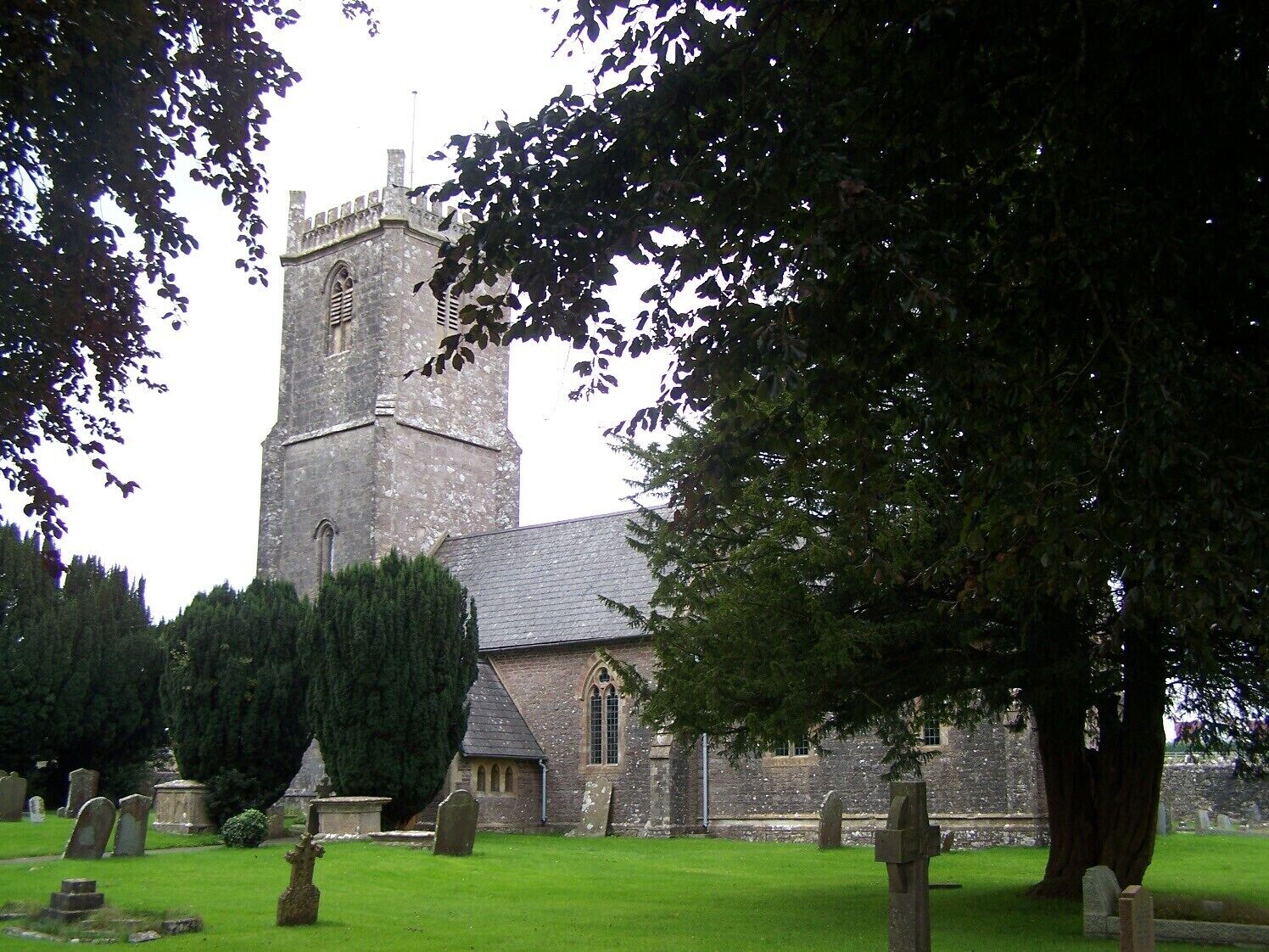 A church with a tall tower and a graveyard with headstones.