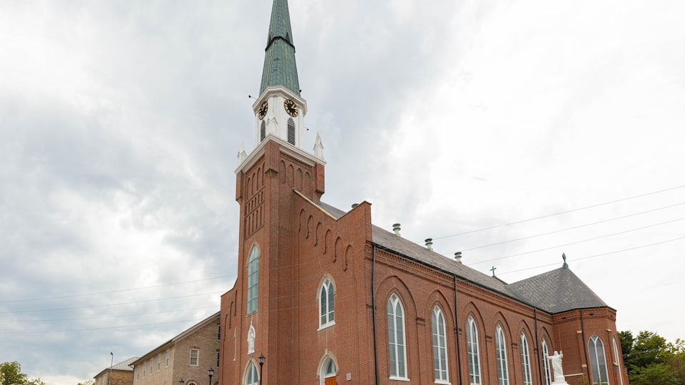 A large brick church with a tall steeple and a clock tower.