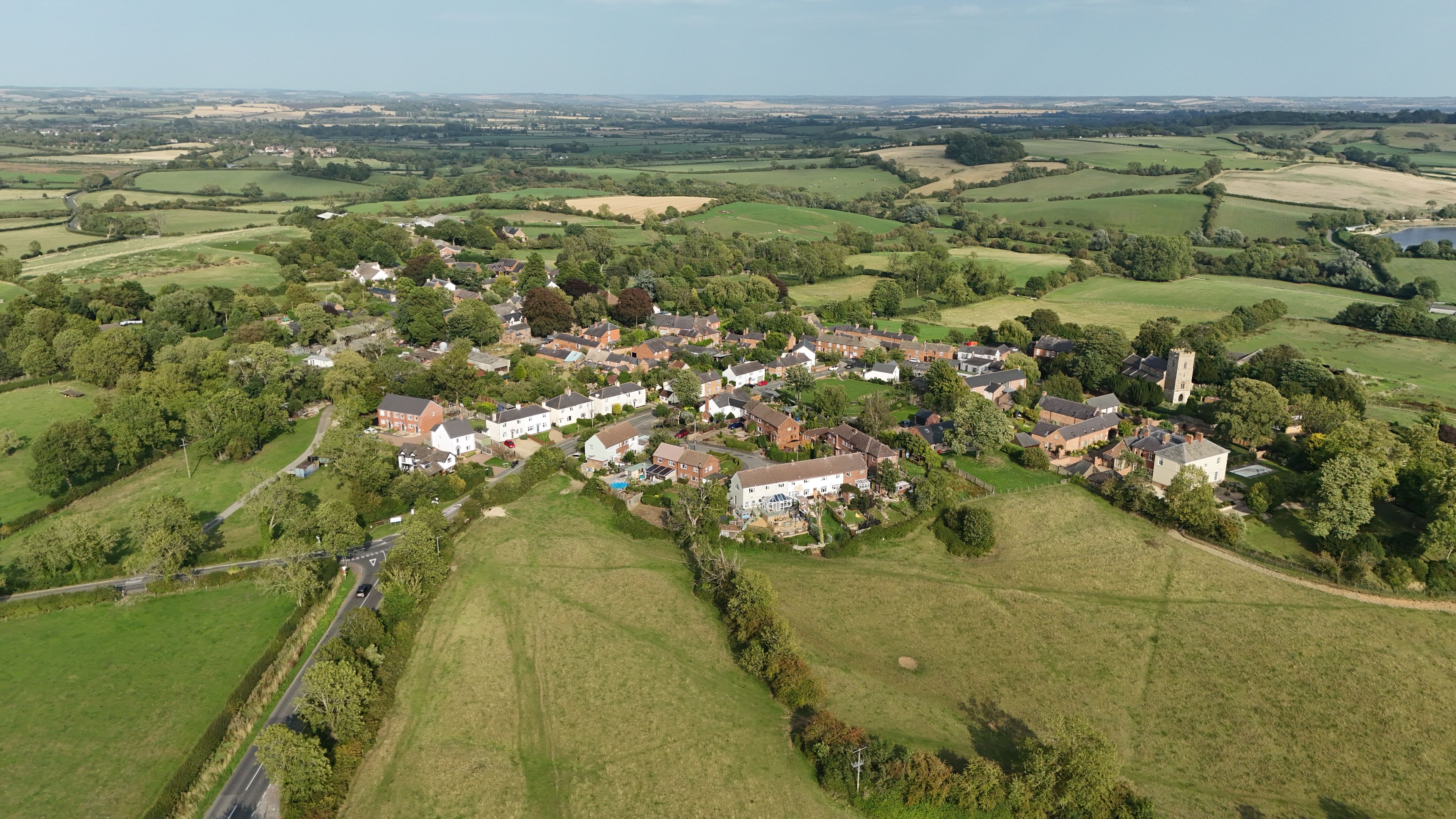 A rural village with houses, a church, and surrounding fields.