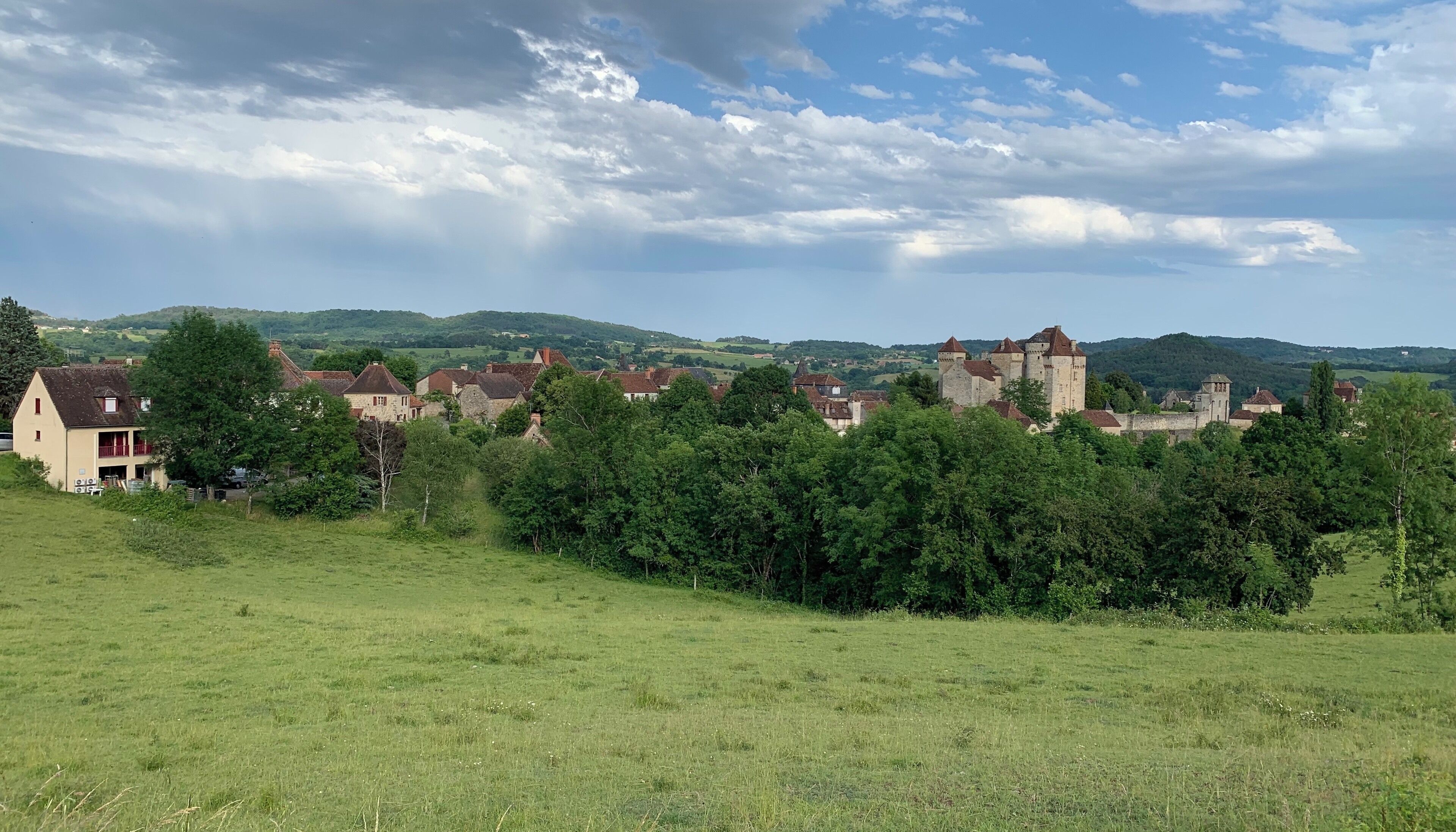 A rural landscape with a castle, houses, and rolling hills.