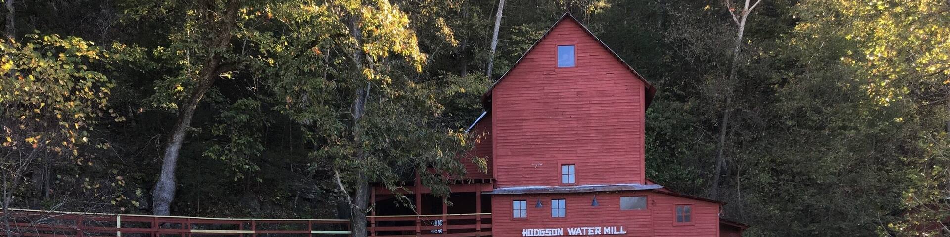 A red watermill with a wooden walkway and a waterfall.