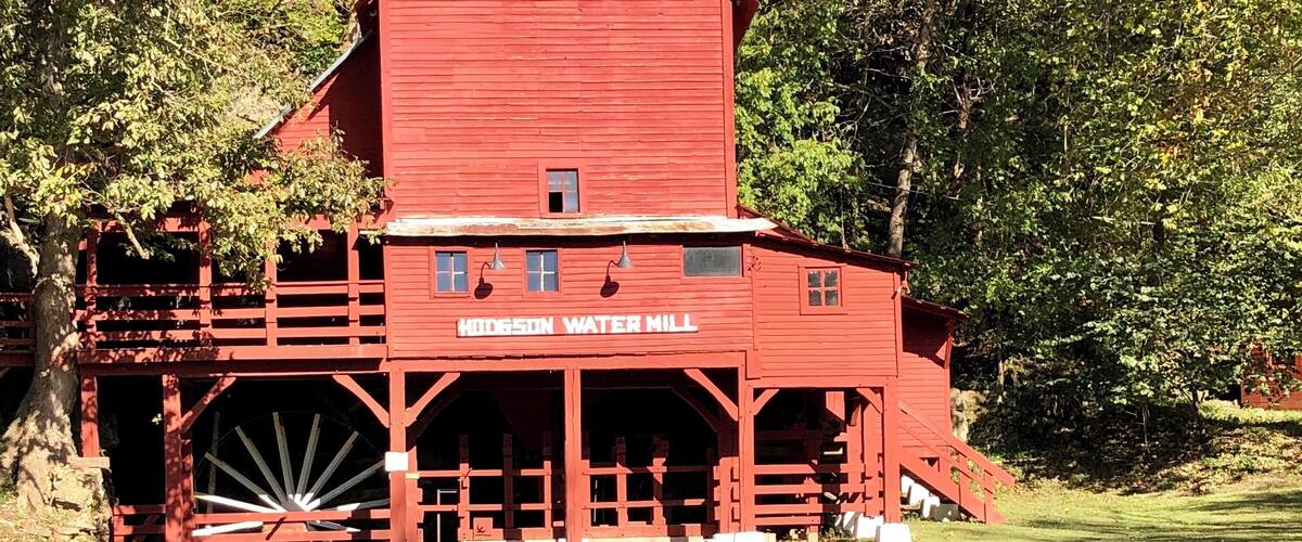 A red water mill with a waterfall in front.