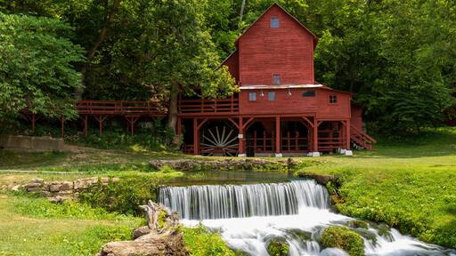 An old red grist mill with a small waterfall.