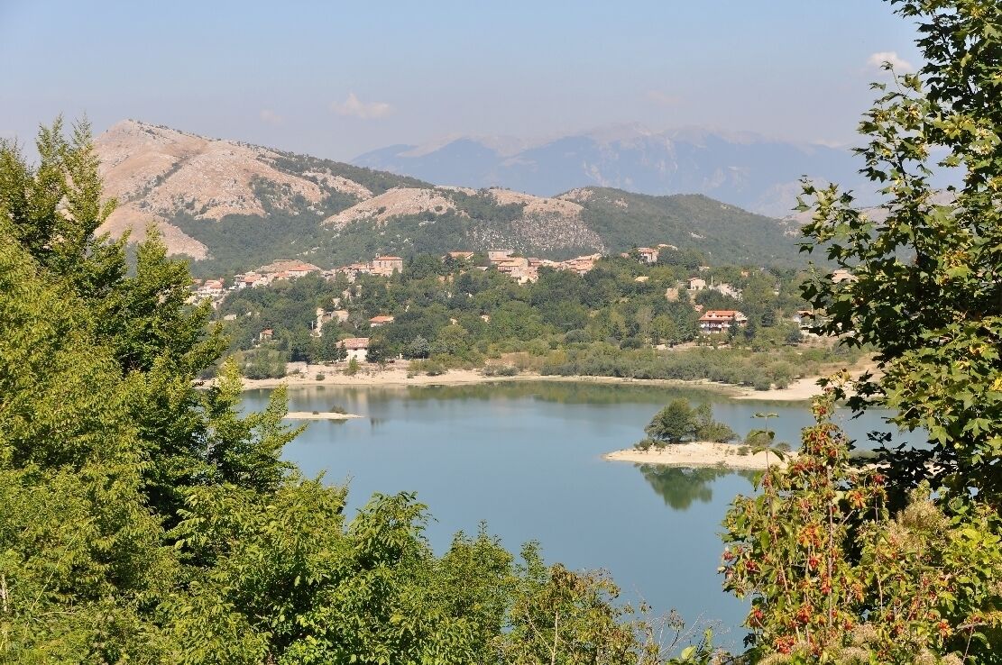 A lake surrounded by mountains, trees, and buildings.