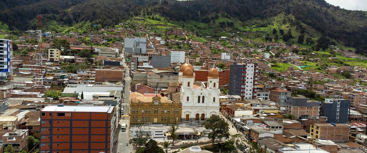 A cityscape with a prominent church, a mix of residential and commercial buildings, and a mountainous backdrop.