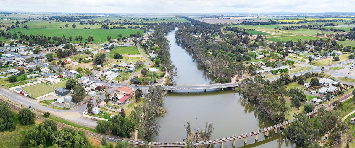 A river flowing through a town with a bridge crossing it.