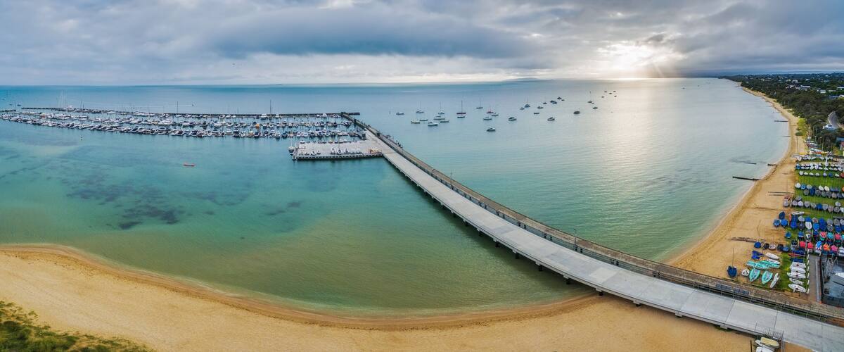 A coastal marina with boats, a pier, and a beach.