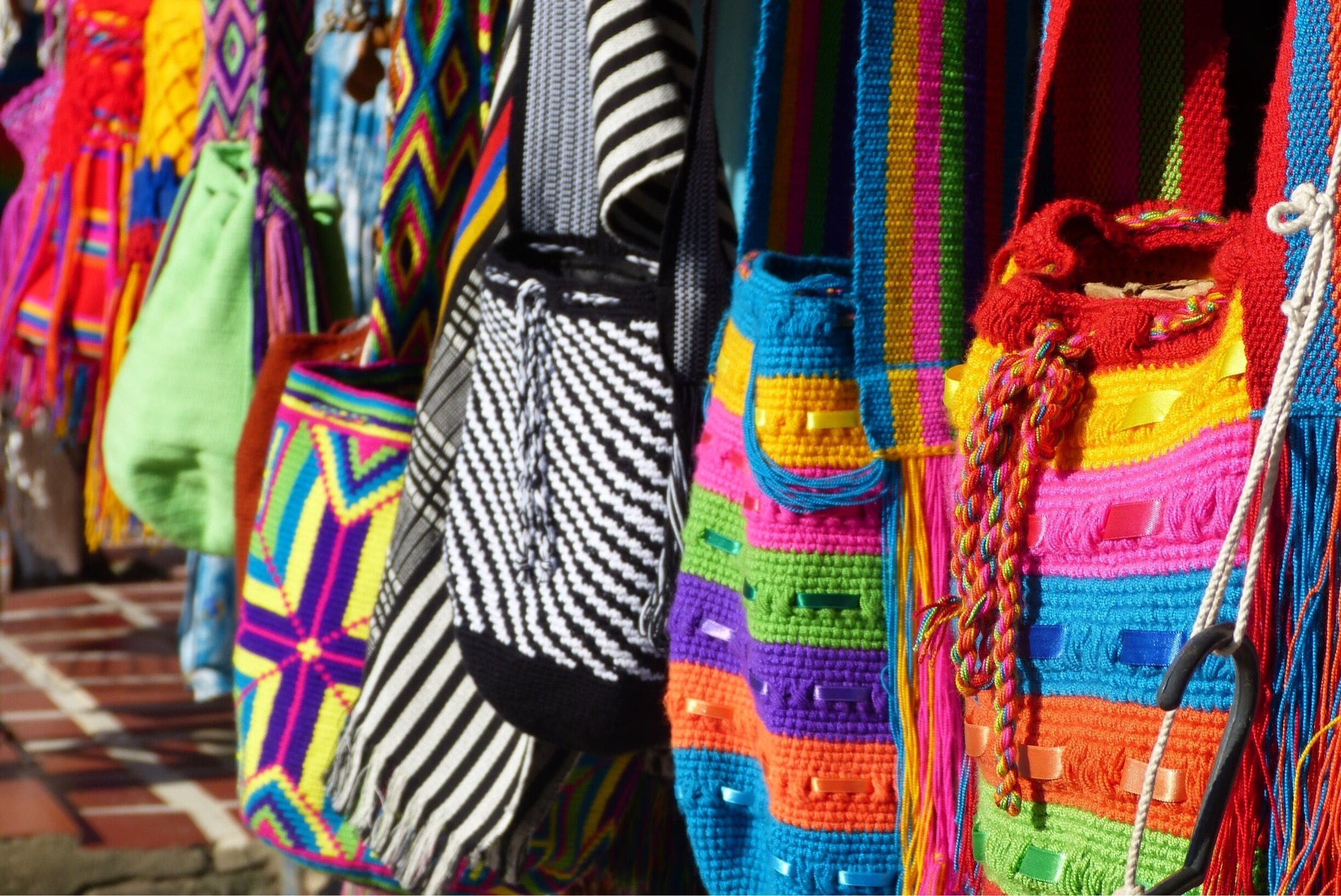 A variety of colorful, handwoven bags and accessories displayed for sale.