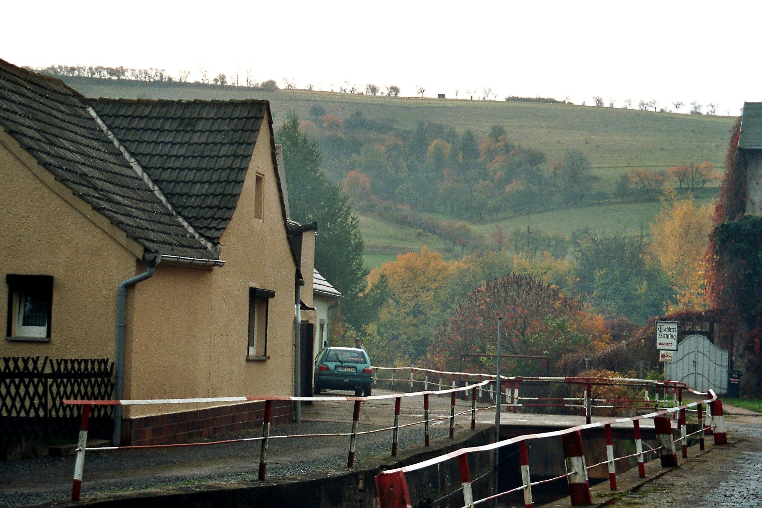 A house with a sloped roof, a car parked in front, and a sign indicating a private road.