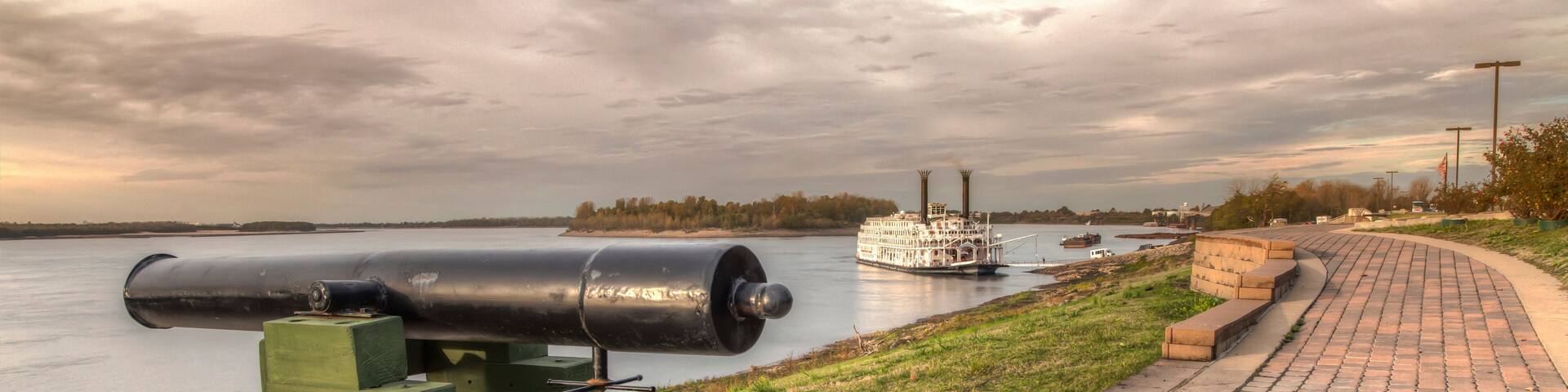 Mississippi River Walk at New Madrid. A magnificent view of the Mississippi river from atop of the levee. A steamboat is docked down river. .