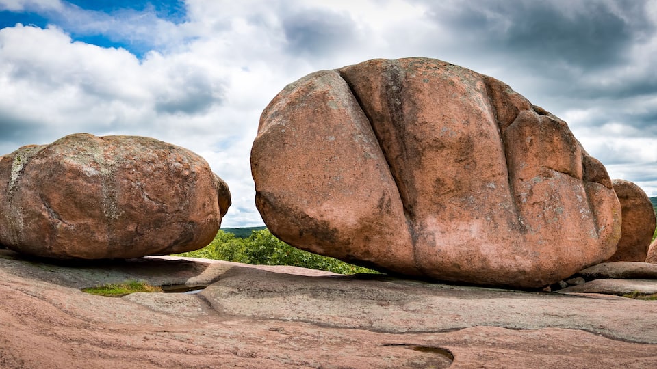 Large boulders on a rocky landscape with a cloudy sky.