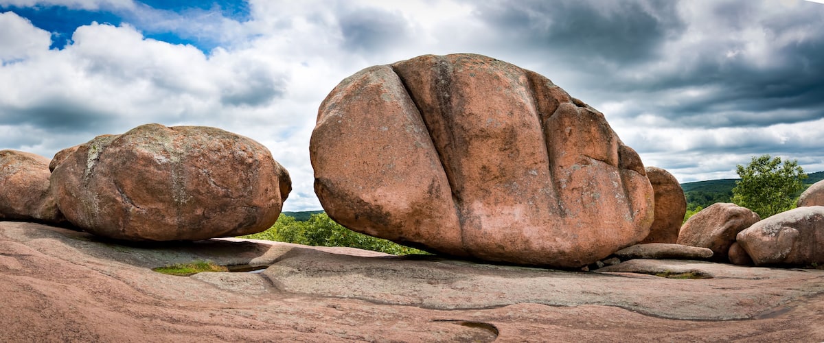 Large boulders on a rocky landscape with a cloudy sky.