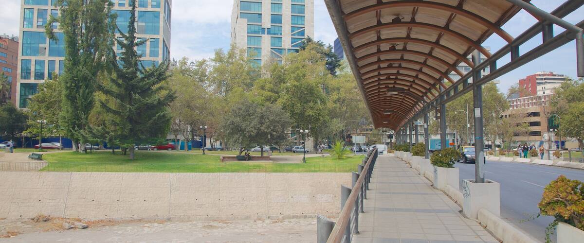 A covered pedestrian walkway with a view of modern buildings and trees.