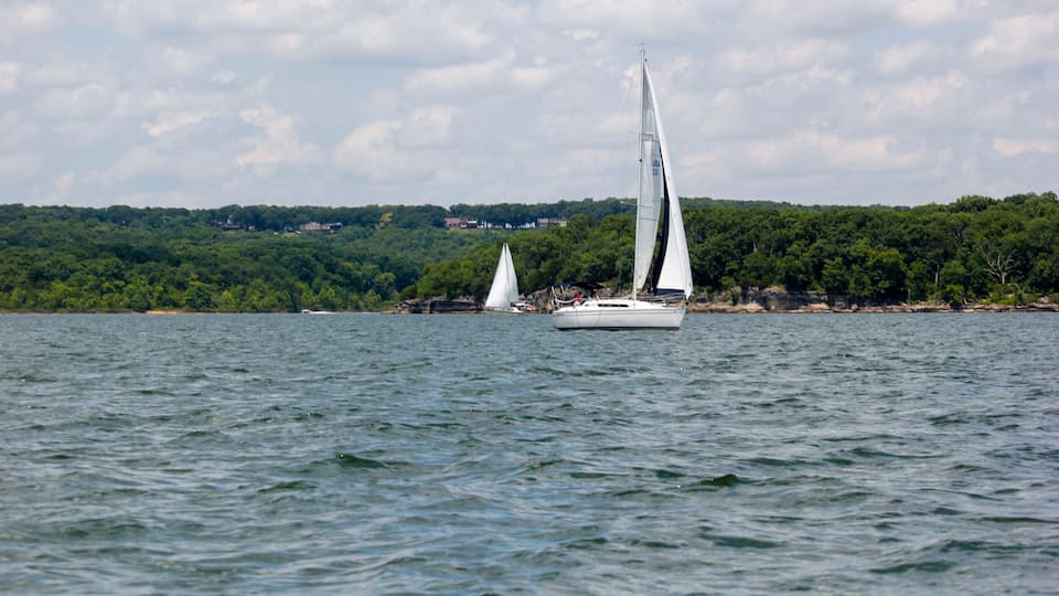 A sailboat on a lake with a forested shoreline in the background.