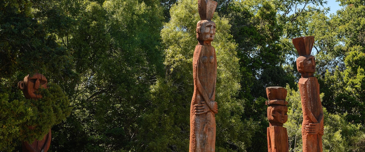 A series of ancient wooden statues in a forested area.