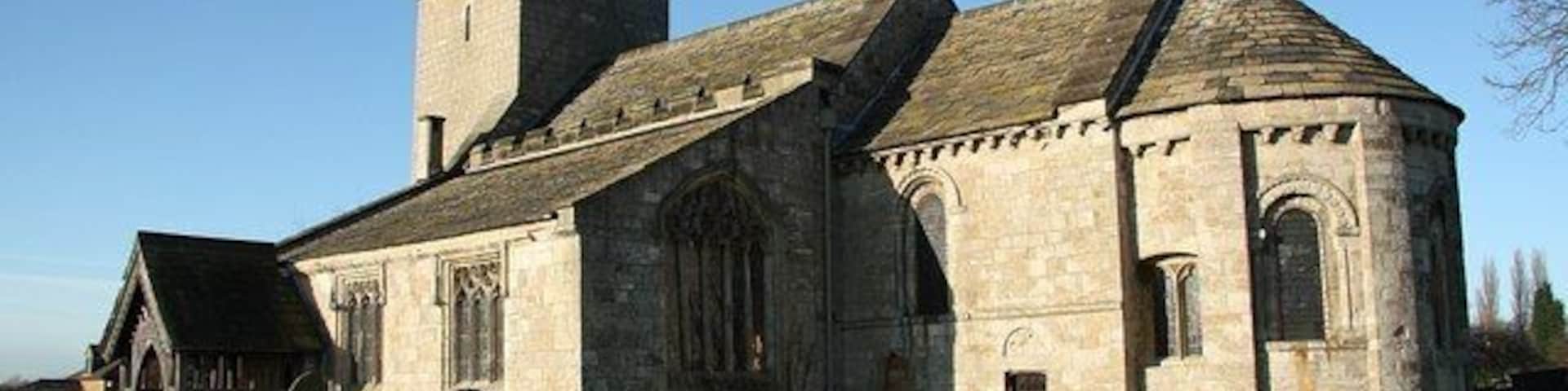 Una iglesia histórica con una alta torre y un cementerio al frente.
