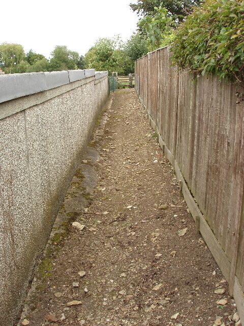 Public footpath behind garages in Yardley Hastings. A local remarked "found it, then!" when he saw me on this path - the entry didn't look like a public footpath, it looked like a bit of land left over when the garages were built. But the path had been signed from Castle Ashby Road, and was signed across the fields. It runs behind houses shown in 525141.
