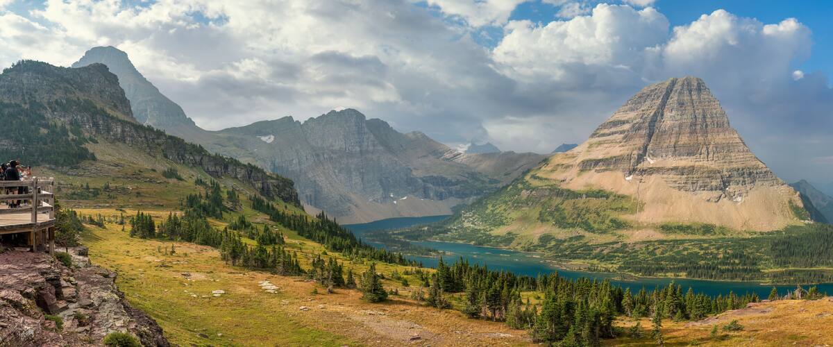 A mountain landscape with a prominent peak, a lake, and a wooden viewing platform.