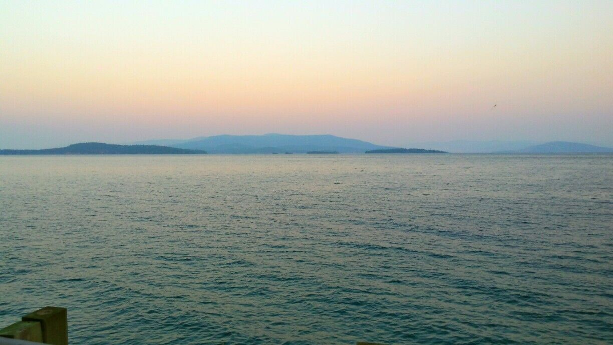 A calm sea with distant landforms under a clear sky.