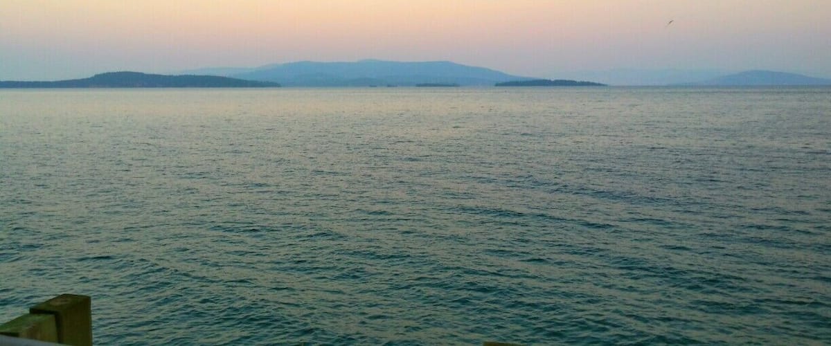 A calm sea with distant landforms under a clear sky.