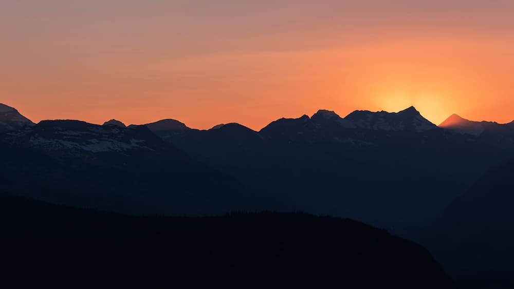 A mountain range silhouetted against a sunset.
