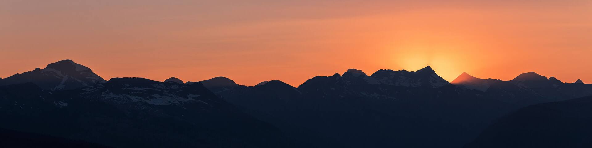 A mountain range silhouetted against a sunset.