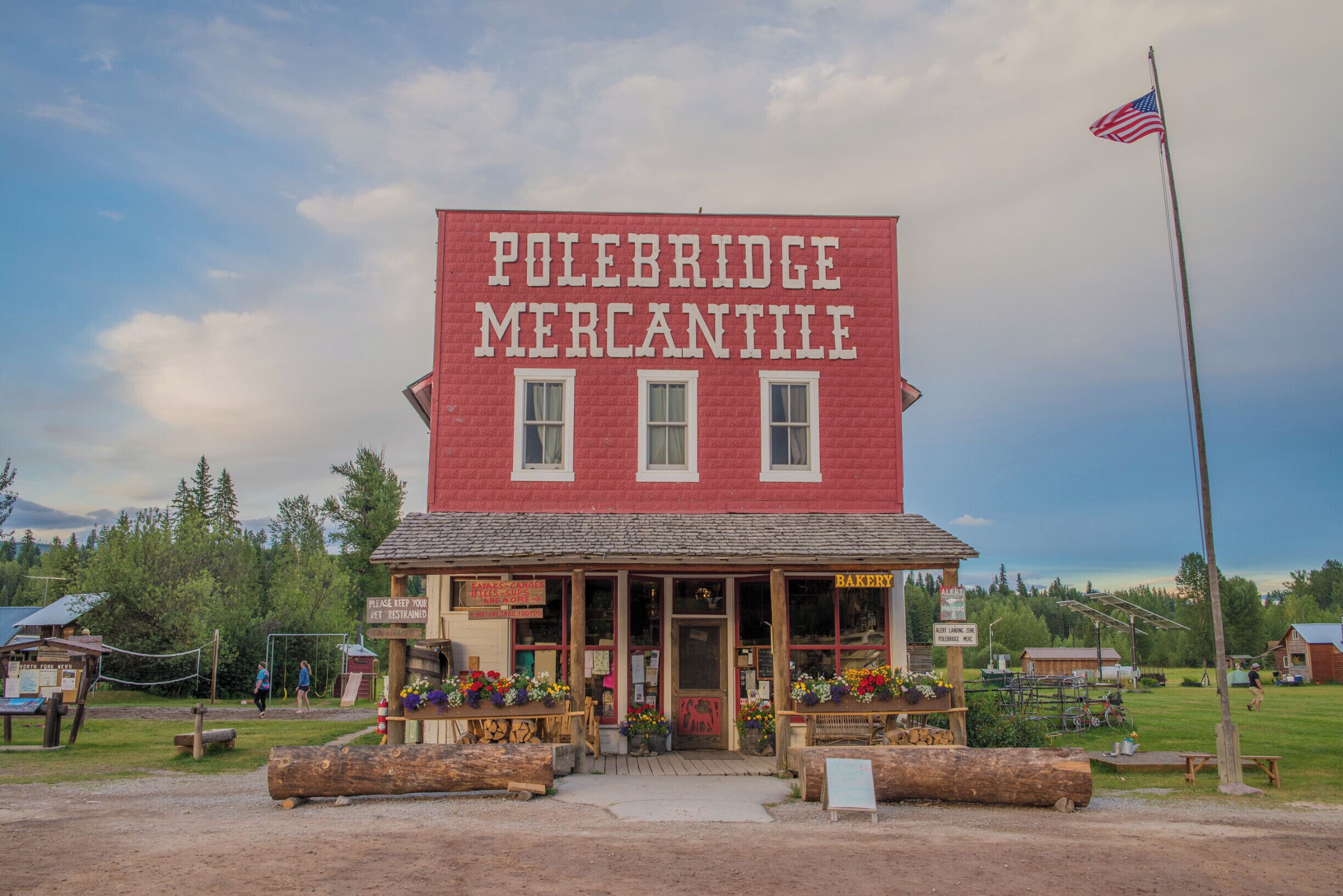 Un edificio rojo con un letrero que dice "Polebridge Mercantile" y una bandera estadounidense.