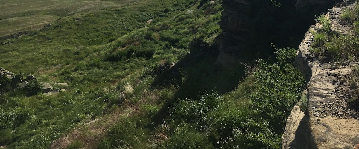 A vast grassy plain with a rocky cliff edge.
