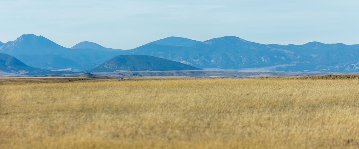 A vast open field with distant mountains under a clear sky.